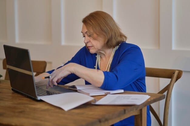 An older woman sitting at a desk with a laptop, reviewing documents related to Social Security benefits. She appears focused and thoughtful, with a calculator and pen nearby.