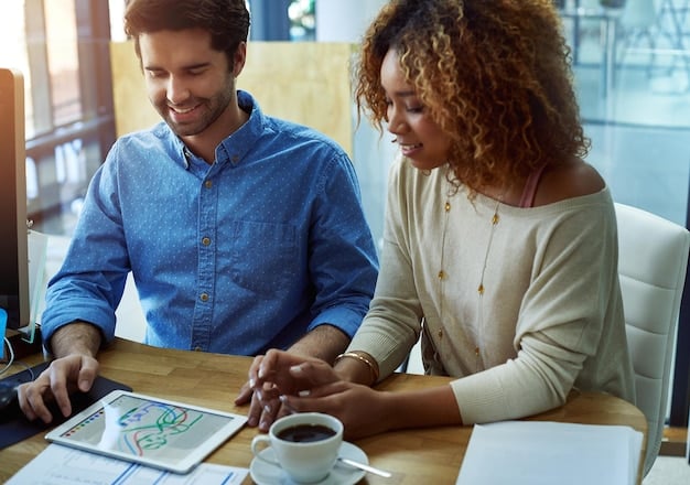 A financial advisor explaining spousal benefits to a couple in their office. The advisor is pointing to a chart illustrating different claiming scenarios.