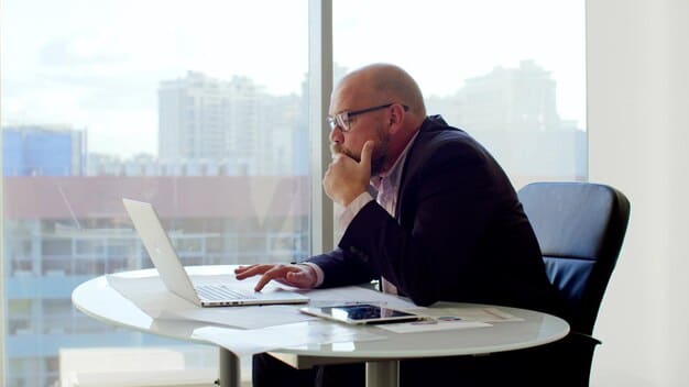 A government employee sitting at his or her desk while thinking about retirement options, with sunlight falling over him or her.